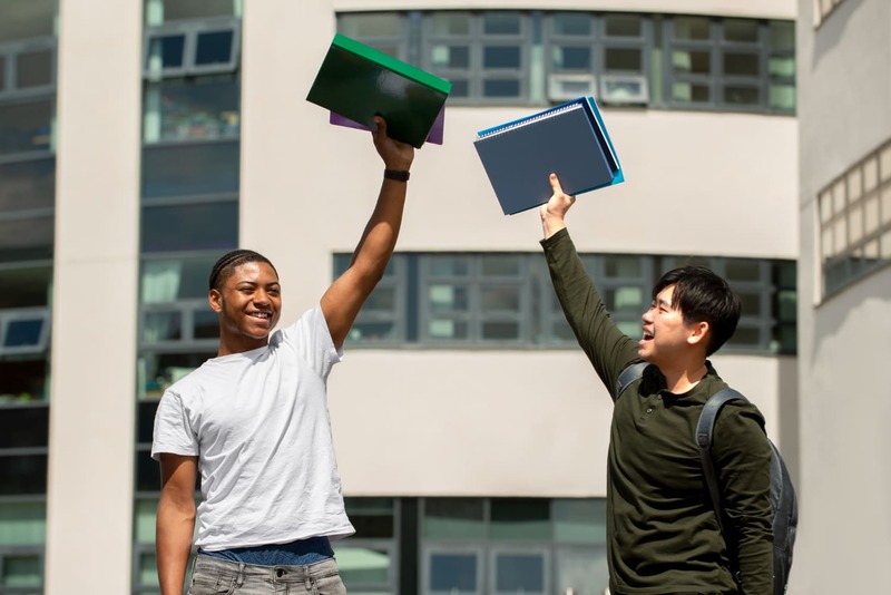 Jovens Comemorando com Livros e Cadernos na Mão